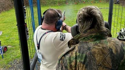 Chris with a member of staff stood behind him while he shoots at small targets